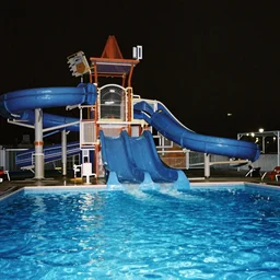 2 0 0 0 s waterpark blue water slide empty pool liminal nighttime dark with weak camera flash