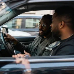 un uomo all'interno della sua auto parcheggiata ad Harlem parla con un tizio dal finestrino