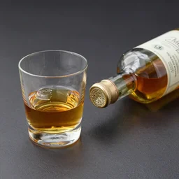 a glass of whiskey and a bottle spilled on the desk