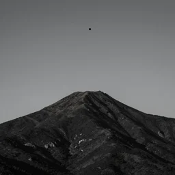 a black dot in the sky stretching a mountain up towards it, dark lighting, landscape
