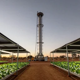 torus shaped electrostatic water condensation collector tower, irrigation system in the background, racks of vegetables propagated under shadecloth,  in the middle of the australian desert, XF IQ4, 150MP, 50mm, F1.4, ISO 200, 1/160s, natural light at sunset with outdoor led strip lighting