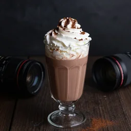 food photography of hot chocolate drink in tall glass with cream on top and cocoa powder, canon macro lens, moody lighting, front view