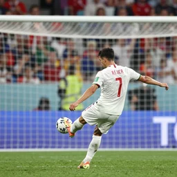 Footballer about to kick a ball into a goal, high shutter speed, sports photography, taken from behind, at the World Cup