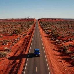 a long road in the red australian outback. a lone blue car is seen driving away from the viewer