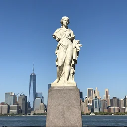 the marble statue of katniss everdeen stands atop a large plinth with new york harbour below