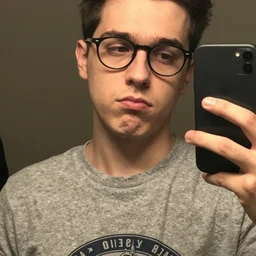 nerd with a blank expression while wearing a graphic t - shirt and taking a selfie, grainy quality, low quality, low resolution, realistic, hyperrealistic, very realistic, hd quality, intricate details, very detailed, grainy, taken on an iphone, awkward angle, awkward lighting