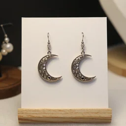 jewelry design, jewelry display, a pair of ornate earrings in the shape of a moon
