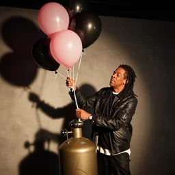 jay-z filling up balloons from a helium tank at a party, photo
