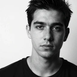 A large-format portrait of a handsome man behind a white backdrop, spot-lighting, depth of field, high contrast, black and white, grainy