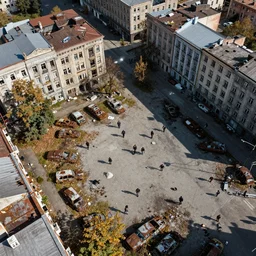 top down aerial view of dilapidated city square in real life, desolate with zombies, dilapidated, zombies in the streets, nightmarish, some rusted style parked vehicles, sunny weather, few clouds, volumetric lighting, photorealistic, daytime, autumn, sharp focus, ultra detailed, cgsociety