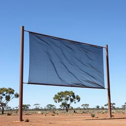 rectangular fog fence rippling in the wind hanging from two towers in the australian outback