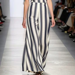 high key lighting model wearing vertical stripes and dramatic palazzo pants on the runway. major glow - up. new variations of color give relaxed cuts and structure. couture. high fashion. fashion week