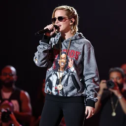 dlsr photography f/1.4 80mm bokeh full body Emma Watson singing on rap concert stage with mic wearing designer hoodie as doja cat as cardi b wearing gold chain and sunglasses and gold hoop earrings