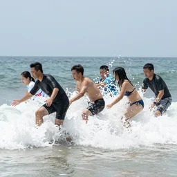 A group of people trying their best to hold back and stop waves at the beach