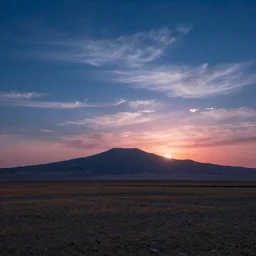 A highly detailed matte painting of A vast and empty landscape with a single mountain in the distance. The sky is a deep blue, with wispy clouds. The sun is setting behind the mountain, casting a pink and orange glow across the scene, by John Howe, trending on artstation.