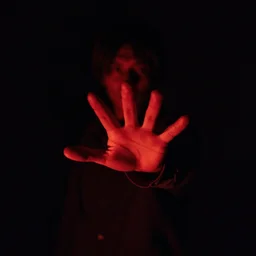Tension building scene someone coming out of pitch black darkness with hand grasping toward the camera, red light, horror movie, Movie Cinematography