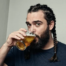 colin farrel with black forked braid beard thick eyebrows drinking a pint of beer