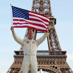 Richard Hammond holding up the flag of america on top of the eiffel tower